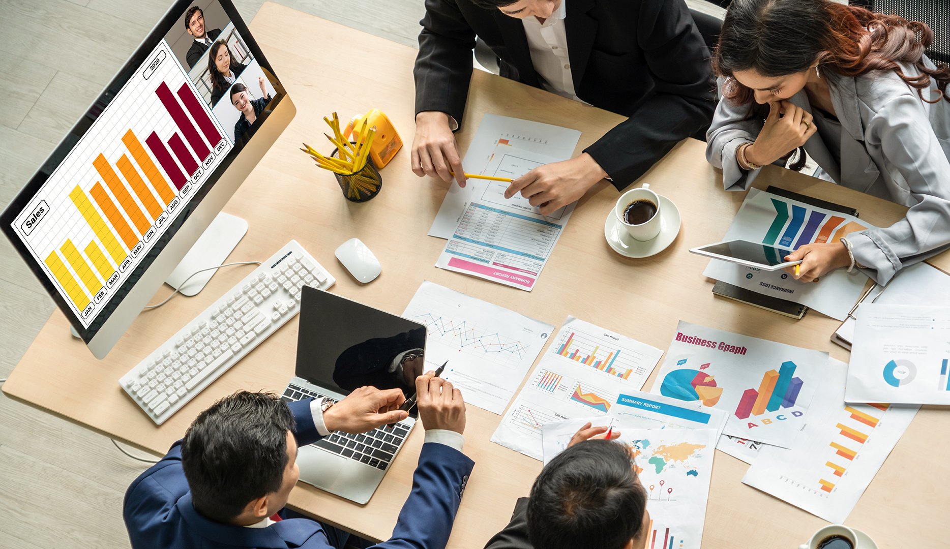 A business meeting with four people analyzing charts and graphs at a desk.