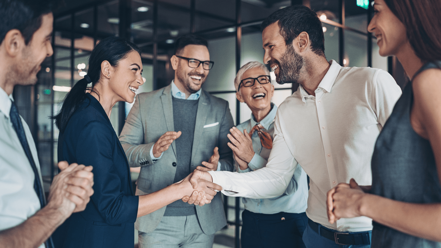 Business colleagues shaking hands and celebrating in a modern office.