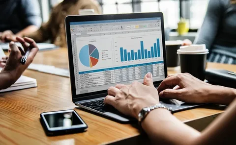 Person working on a laptop displaying charts and graphs during a meeting.