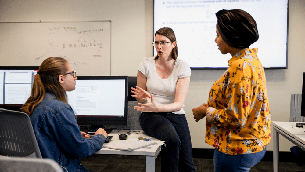 Educator presents institutional research and enrollment data to colleagues at a post-secondary support meeting.